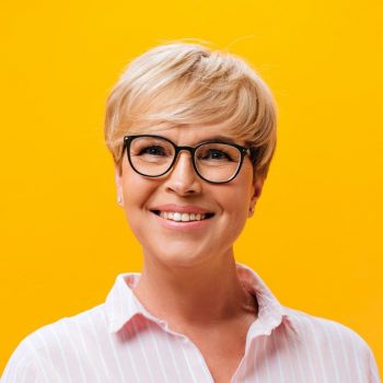 happy-lady-in-eyeglasses-and-pink-shirt-smiling-on-orange-background-e1627382664932.jpg